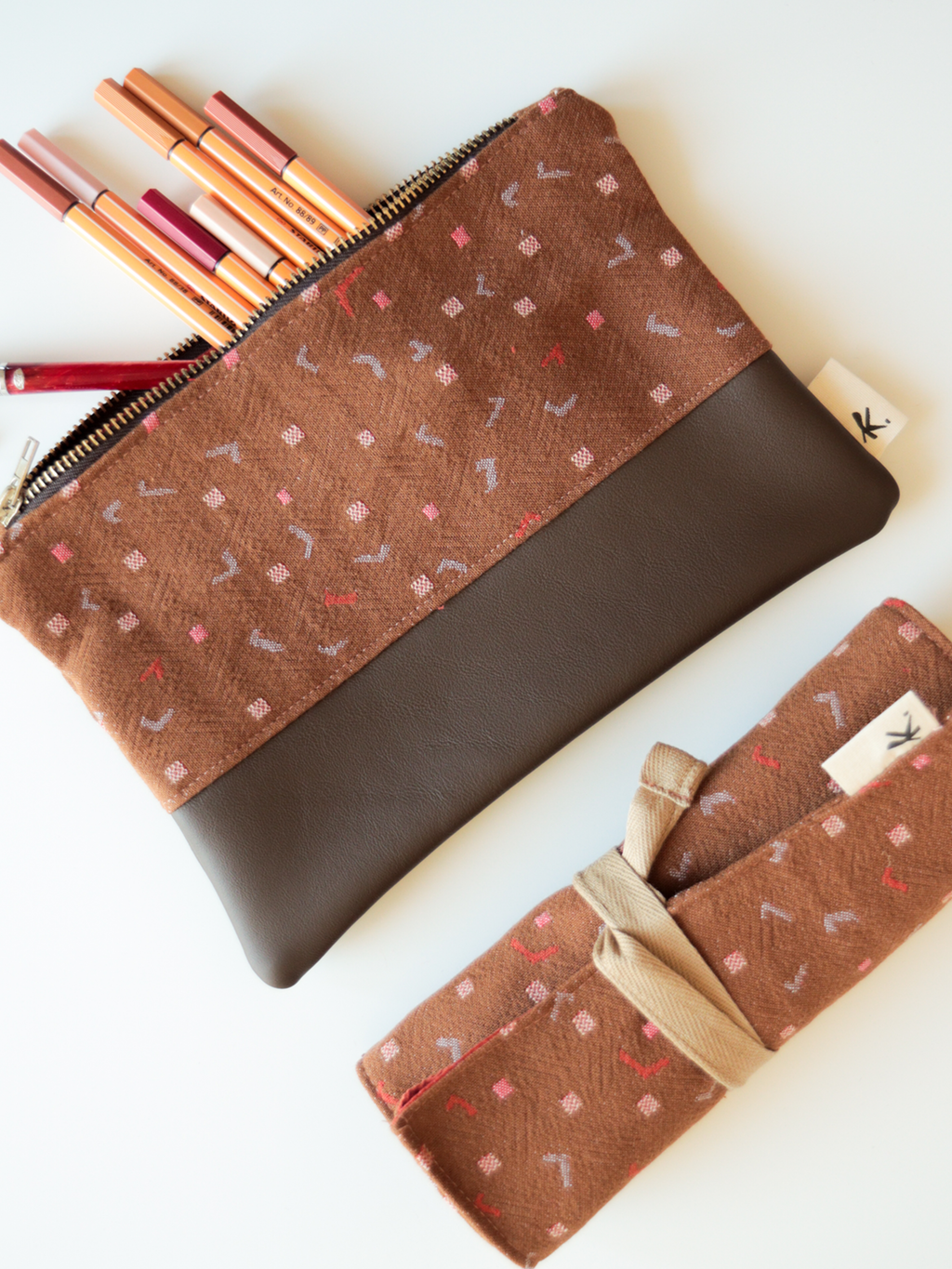 Dettaglio degli astucci pochette Terracotta in tessuto fantasia marrone e pelle, con chiusura a zip metallica